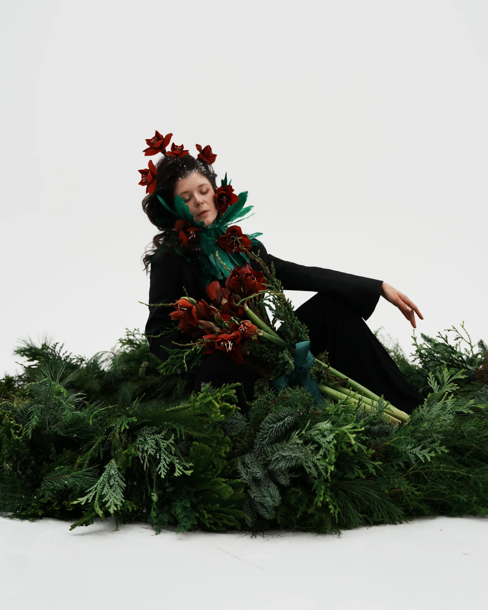 Woman with red flowers surrounded by lush evergreen Christmas foliage