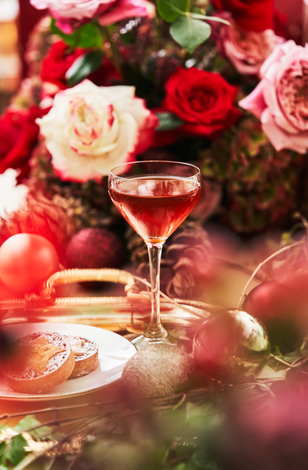Festive dining table with roses, Christmas ornaments and a stemmed glass on a gold tray